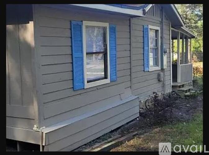 A small house with blue shutters is for sale.