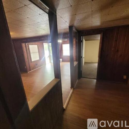 A room with wooden floors and a window on the left side.