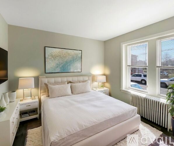 A bedroom with a large bed, two lamps, and a painting on the wall.