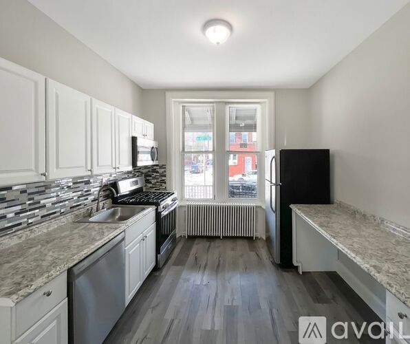 A kitchen with white cabinets and a black refrigerator.