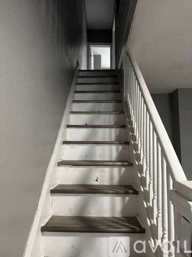 A staircase with a white railing and brown steps.