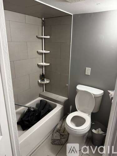 A white toilet in a small bathroom with a bathtub and a towel rack.