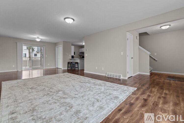 A spacious living room with a rug, chairs, and a bar area.