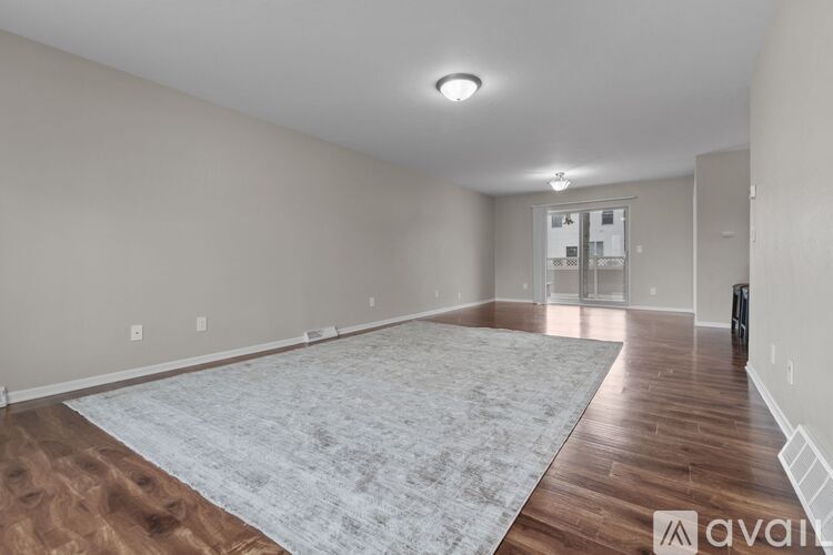 A spacious room with wooden flooring and a grey rug in the foreground.