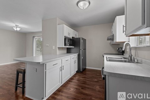 A kitchen with white cabinets and a wooden floor.