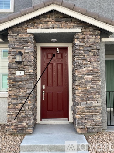 A red door is flanked by two stone pillars.