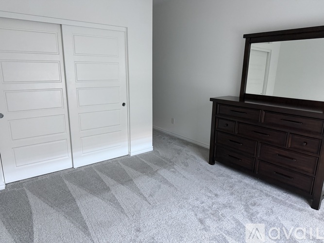 A bedroom with a dresser and two doors.