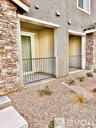 A house with a balcony and a gravel area in front.