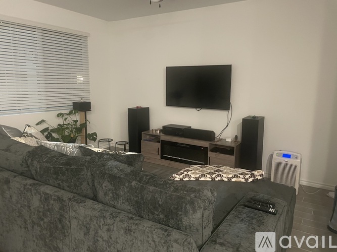 A living room with a grey couch, a flat screen TV, and a speaker system.