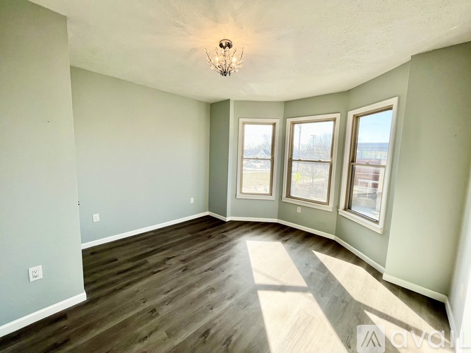 A room with a wooden floor and three windows.