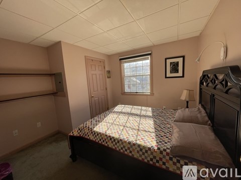 A bedroom with a bed, dresser, and window.