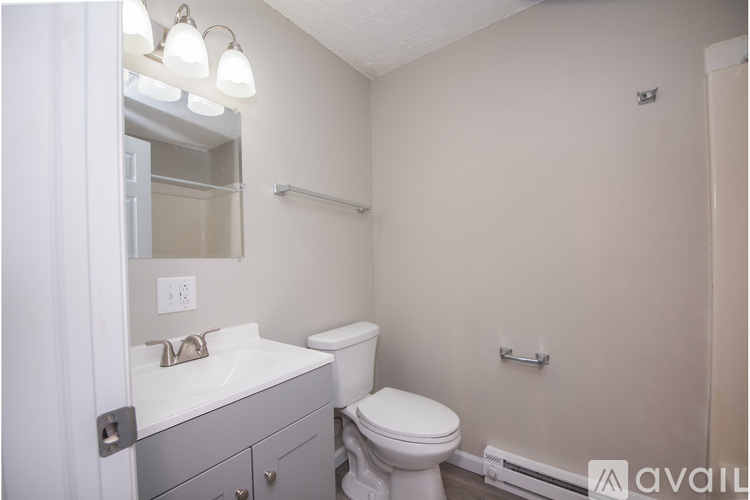A bathroom with a toilet, sink, and mirror.