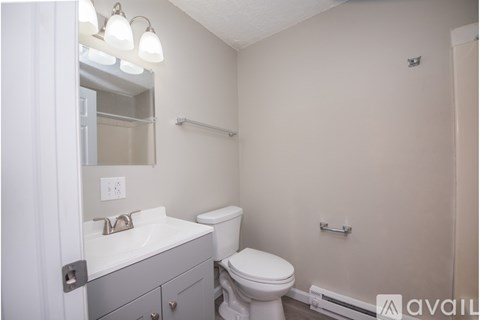 A bathroom with a toilet, sink, and mirror.