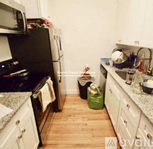 A kitchen with a black fridge and white cabinets.