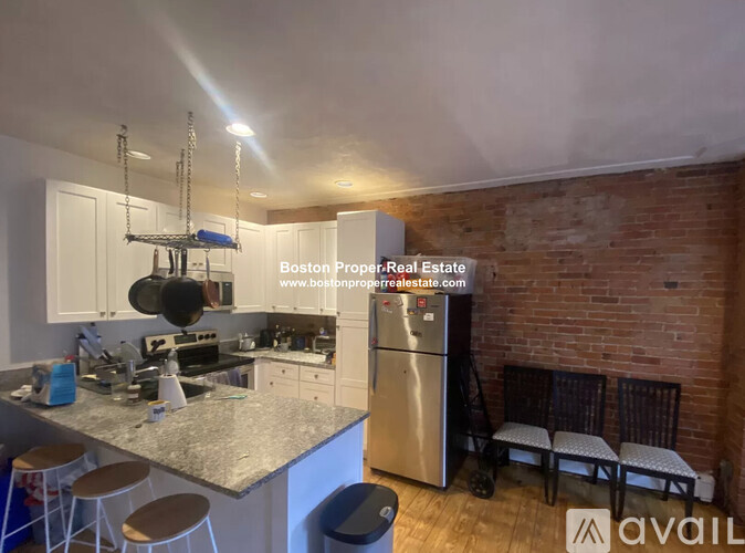 A kitchen with a refrigerator, stove, and bar stools.