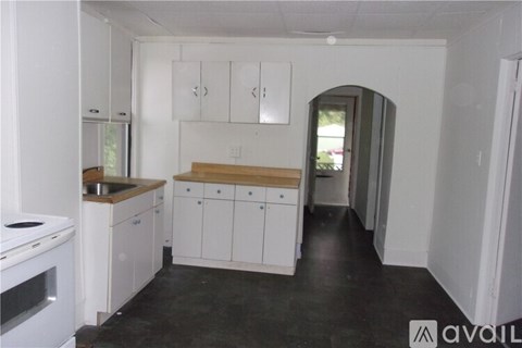 A kitchen with white cabinets and a black floor.