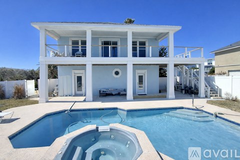 A white house with a pool in front.