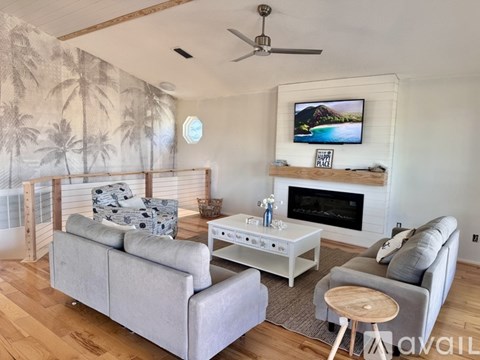 A living room with a grey couch, a white coffee table, and a television on the wall.