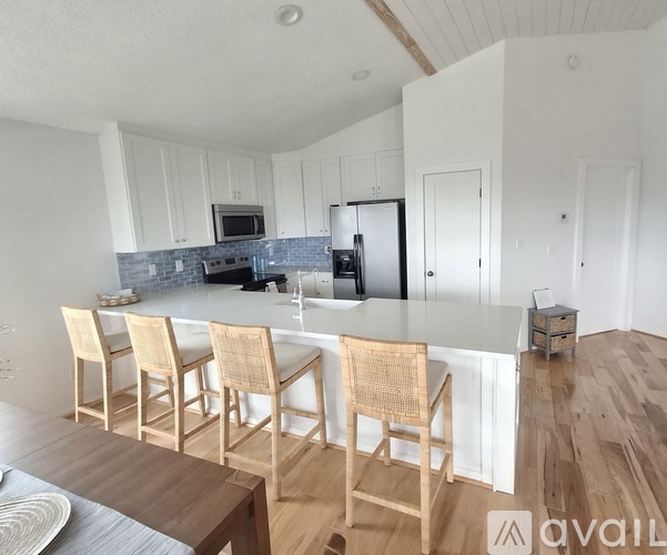 A kitchen with a white countertop and wooden chairs.