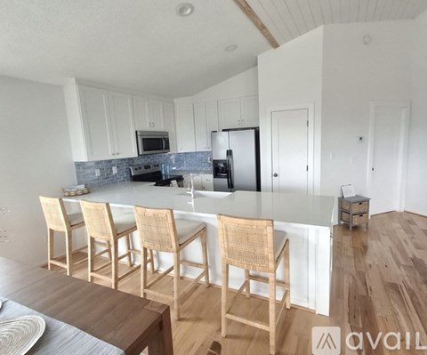 A kitchen with a white countertop and wooden chairs.
