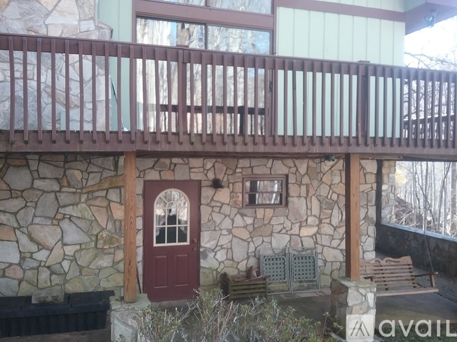 A balcony with a red door and a stone wall.