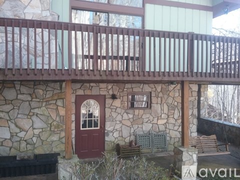 A balcony with a red door and a stone wall.