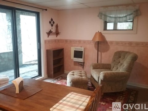 A living room with a chair, ottoman, and a table.