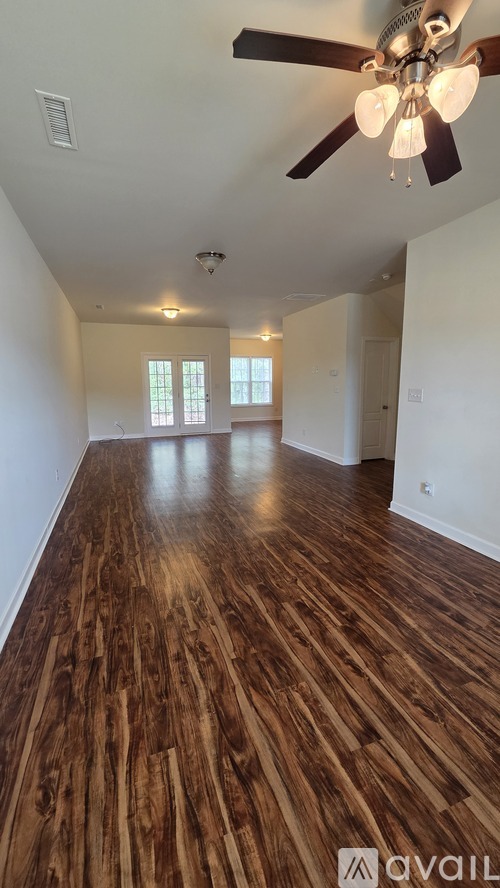 A room with wooden flooring and a ceiling fan.