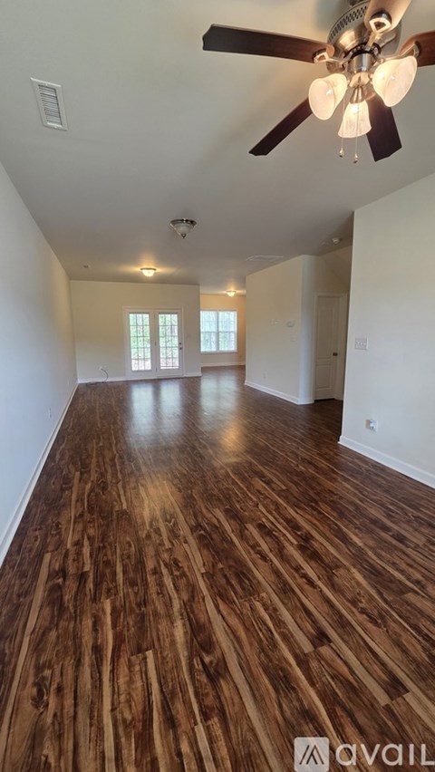 A room with wooden flooring and a ceiling fan.