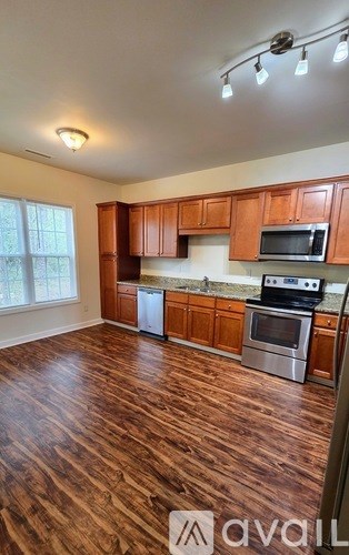 A kitchen with wooden cabinets and stainless steel appliances is available for rent.