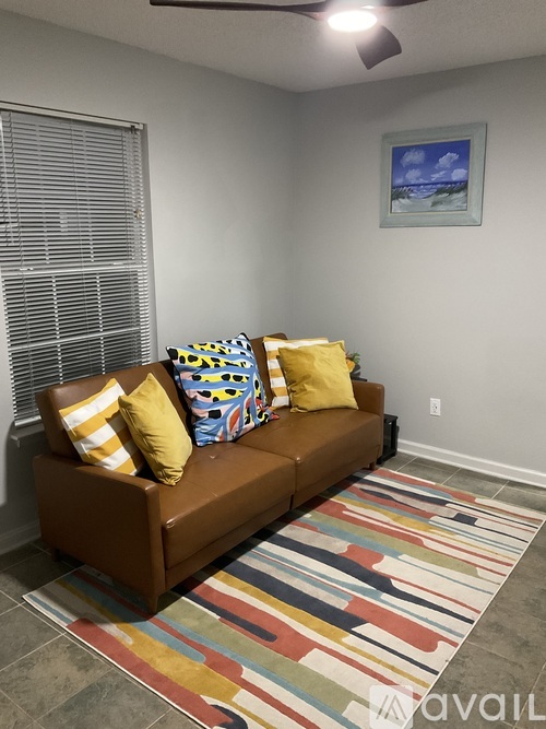 A living room with a brown couch and a colorful rug.