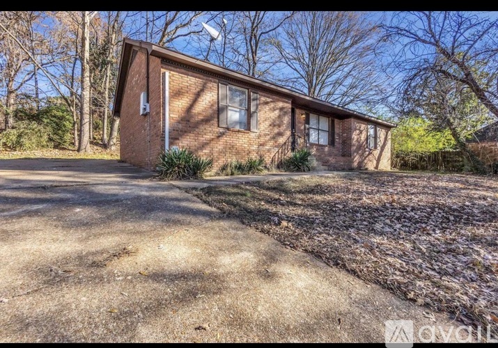 A small brick house with a driveway in front.