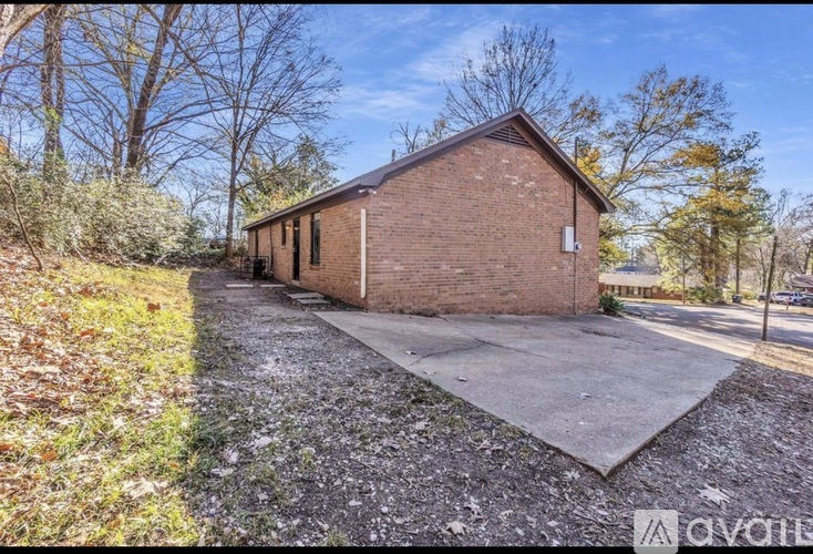 A small brick building with a gravel driveway in front.