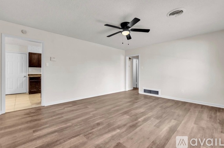 A room with a ceiling fan and wooden flooring.