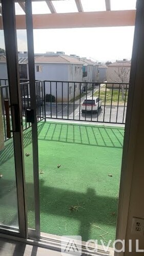 A balcony with a glass door leading to a green area.