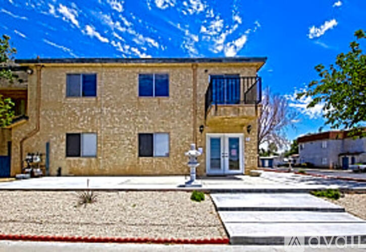 A tan stucco house with a red brick walkway in front.