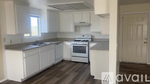 A kitchen with white cabinets and a white stove top oven.