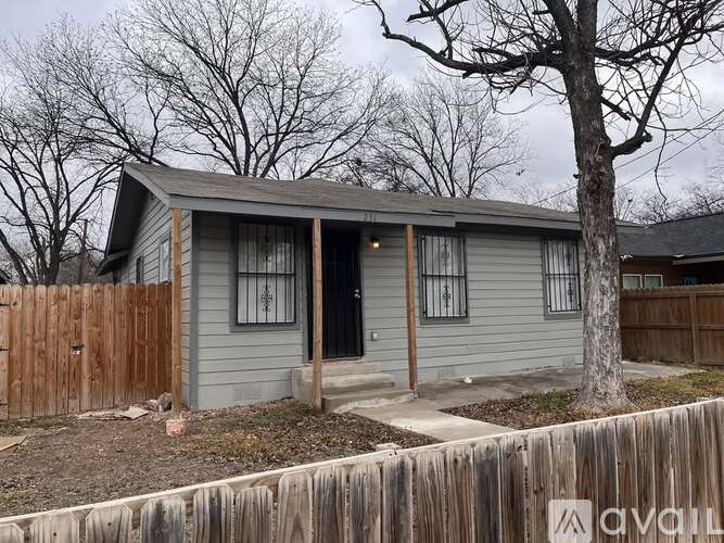 A small house with a grey roof and a wooden fence in front.
