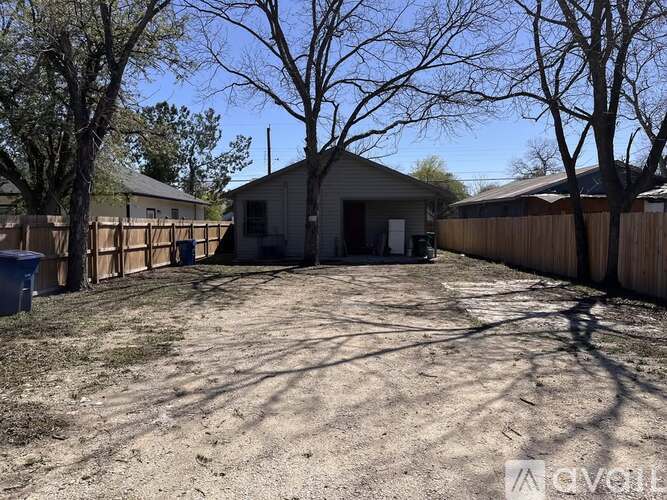 A backyard with a fence and a house in the background.