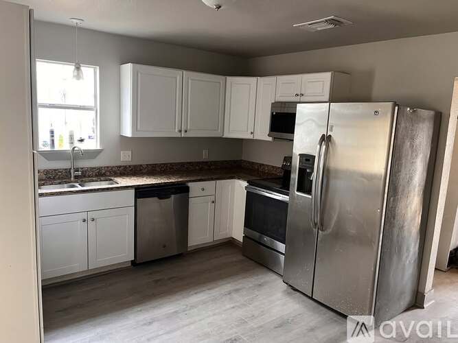 A kitchen with a refrigerator, microwave, oven, and sink.