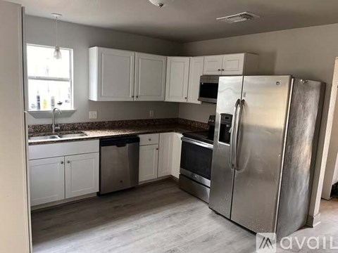 A kitchen with a refrigerator, microwave, oven, and sink.