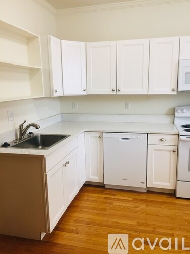 A kitchen with white cabinets and a wooden floor.