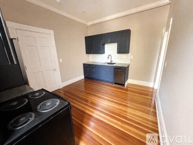 A kitchen with a black stove top oven and wooden flooring.