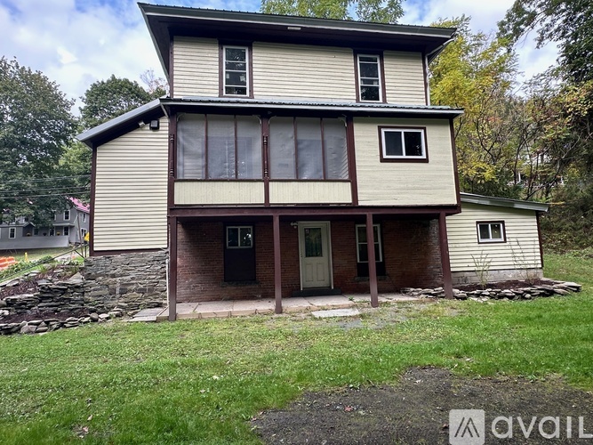 A two-story house with a stone foundation and a green lawn in front.