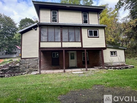 A two-story house with a stone foundation and a green lawn in front.