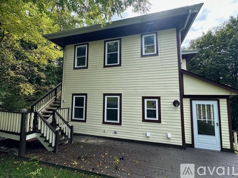 A house with a white door and windows is surrounded by trees.
