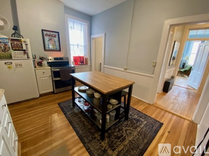 A kitchen with a white fridge and wooden floors.