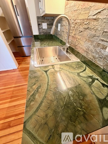 A kitchen with a stone wall and a sink.
