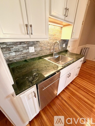A kitchen with white cabinets and a green marble countertop.