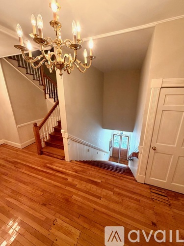 A chandelier hangs over a wooden staircase.